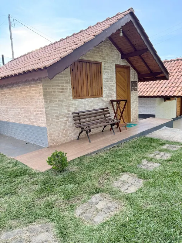 Fachada do chalé com banco na varanda e gramado