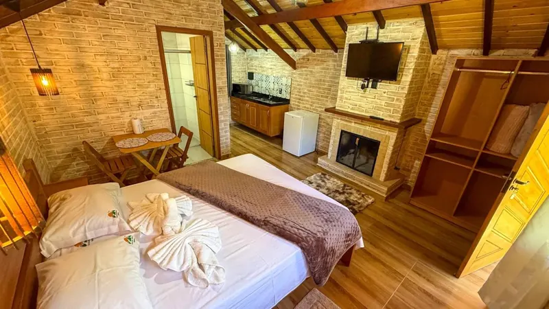 Quarto do chalé com teto de madeira e lareira