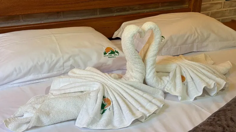 Toalhas dobradas em forma de cisnes formando um coração sobre a cama
